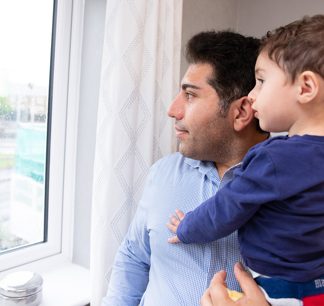 father-holding-small-child-next-to-window